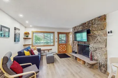 a living room with a stone fireplace and a tv at Hi Country 816 in Winter Park