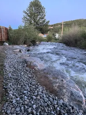 a river with rocks on the side of it at Thorpe On The Water. Creekside Nederland Cabin. in Nederland