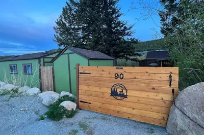 a wooden fence in front of a house at Thorpe On The Water. Creekside Nederland Cabin. in Nederland