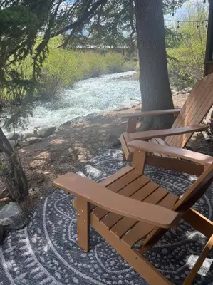 a wooden bench sitting next to a tree next to a river at Thorpe On The Water. Creekside Nederland Cabin. in Nederland