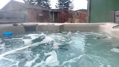 a hot tub filled with water in a backyard at Thorpe On The Water. Creekside Nederland Cabin. in Nederland