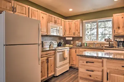 a kitchen with wooden cabinets and a white refrigerator at Cozy Condo on Fall River - 1 Mile to RMNP Gate! in Estes Park