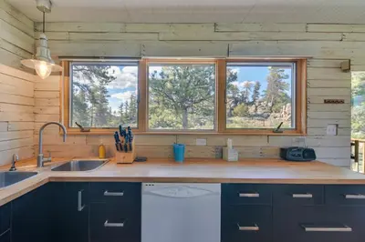 a kitchen with a sink and two windows at Cozy Red Feather Lakes Retreat with Deck and Yard in Red Feather Lakes