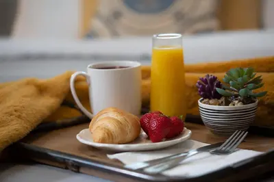 a breakfast tray with a cup of orange juice and strawberries at Cozy Bungalow Hot Tub & Fire Pit, Walk Downtown in Loveland