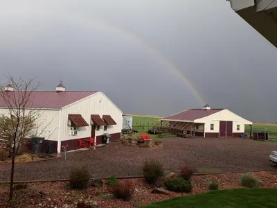a rainbow over a white barn with a yard at Llama-Stay at Spooky Tooth Ranch - Mtn Views! in Loveland