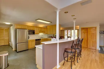 a kitchen with wooden cabinets and a counter with bar stools at Spacious Townhome Near Main St and Lake Dillon! in Frisco