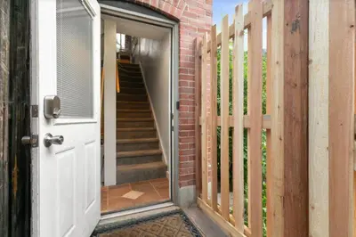 an open door to a brick house with a fence at 1147 Vine St in Denver