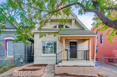 a white house with a porch and a tree at 1020 E 24th Ave in Denver