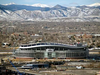a large building with a stadium in front of snowy mountains at 3329 W 31st in Denver