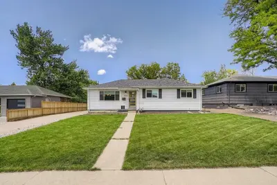 a white house with a large yard withgrass at 5235 E Atlantic Pl in Denver