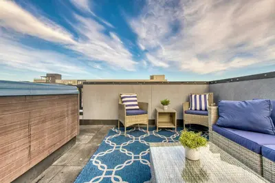 a patio with a couch and chairs on a balcony at Walk to Empower Field Townhome with Hot Tub! in Denver