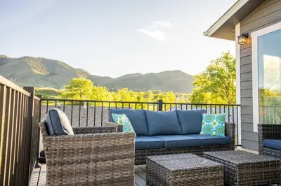 a patio with a blue couch and wicker chairs at Golden Cottage Near Red Rocks and School of Mines! in Golden