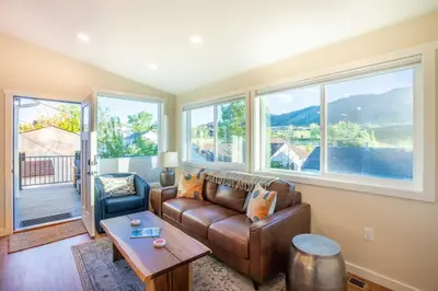 a living room with a couch and a table and windows at Golden Cottage Near Red Rocks and School of Mines! in Golden