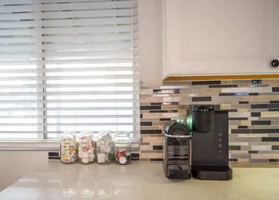 a kitchen with a coffee maker and a brick wall at Modern Retreat With Patio & Sunset Views - Gray St in Arvada