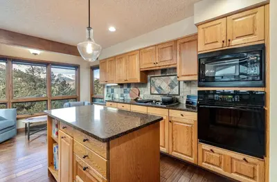 a kitchen with wooden cabinets and a black appliance at Alpenglow Vacation Home at Windcliff home in Estes Park