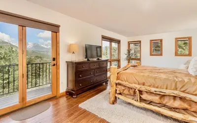 a bedroom with a bed and a television and a balcony at Alpenglow Vacation Home at Windcliff home in Estes Park