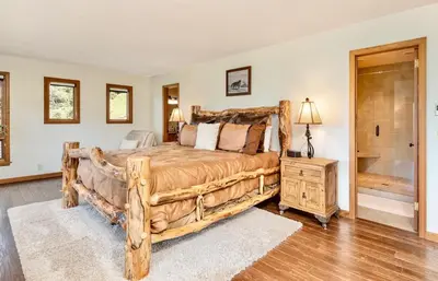a bedroom with a large wooden bed and a bathroom at Alpenglow Vacation Home at Windcliff home in Estes Park