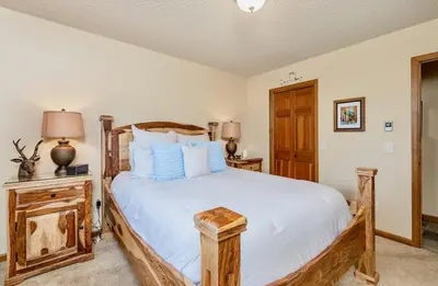a bedroom with a wooden bed with white sheets and blue pillows at Alpenglow Vacation Home at Windcliff home in Estes Park