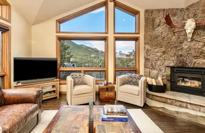 a living room with a fireplace and a stone wall at Alpenglow Vacation Home at Windcliff home in Estes Park