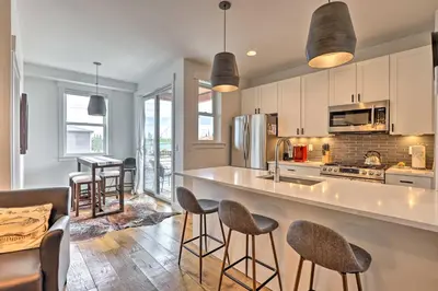 a kitchen with a counter and chairs in a room at Grand Lake Condo with Balcony and Mountain Views in Grand Lake