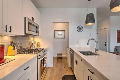 a kitchen with white cabinets and a sink and a stove at Grand Lake Condo with Balcony and Mountain Views in Grand Lake