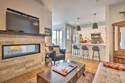 a living room with a fireplace and a tv at Grand Lake Condo with Balcony and Mountain Views in Grand Lake