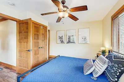 a bedroom with a ceiling fan and a blue bed at Modern Grand Lake Luxury in Grand Lake