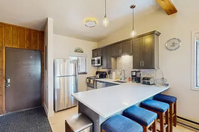 a kitchen with a white counter and blue stools at Rustic Relaxation in Winter Park in Winter Park