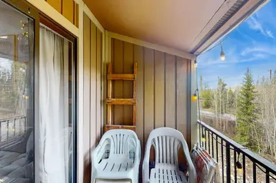 two white chairs sitting on a porch with a window at Rustic Relaxation in Winter Park in Winter Park