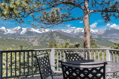 a table and chairs on a balcony with mountains at Cliffview Luxury Vacation Rental at Windcliff home in Estes Park