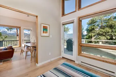 a living room with large windows and a table and chairs at Cliffview Luxury Vacation Rental at Windcliff home in Estes Park