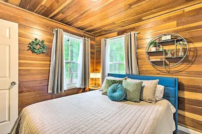 a bedroom with a blue bed with wooden walls at Creekside Morrison Cabin about 9 Mi to Red Rocks Park! in Morrison