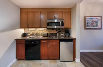 a kitchen with wooden cabinets and a sink and a microwave at Premium Unit 4547 - One Bedroom withKitchenette - Fraser Crossing Founders Pointe condo in Winter Park