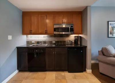 a kitchen with black appliances and wooden cabinets at Premium Unit 4466 - One Bedroom withKitchenette - Fraser Crossing Founders Pointe condo in Winter Park