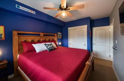 a bedroom with a red bed with a ceiling fan at Premium Unit 4466 - One Bedroom withKitchenette - Fraser Crossing Founders Pointe condo in Winter Park