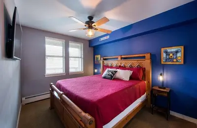 a bedroom with a red bed with a blue wall at Premium Unit 4466 - One Bedroom withKitchenette - Fraser Crossing Founders Pointe condo in Winter Park