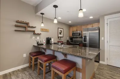 a kitchen with a counter with stools and a refrigerator at Value Unit 4440 - Two Bedroom - Fraser Crossing Founders Pointe condo in Winter Park