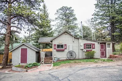 a white house with red doors and a driveway at Prospect Cabin, Cozy 1-bedroom cabin with kitchen Dogs OK in Estes Park