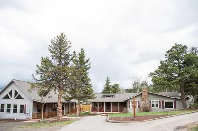a white house with trees in front of it at Prospect Cabin, Cozy 1-bedroom cabin with kitchen Dogs OK in Estes Park
