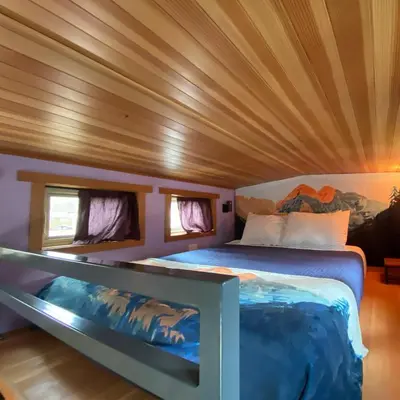 a bed in a room with a wooden ceiling at WeeCasa Tiny Home Resort in Lyons