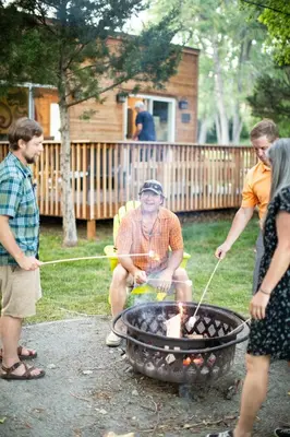 a group of people standing around a grill at WeeCasa Tiny Home Resort in Lyons
