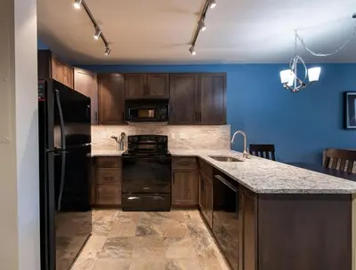 a kitchen with wooden cabinets and a black refrigerator at Zephyr Mountain Lodge Premium-Rated 2516 in Winter Park