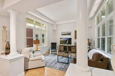 a living room with white furniture and large windows at Quiet Urban Escape - Backs to Poudre River Trail! in Fort Collins