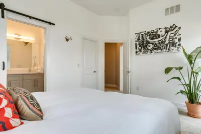 a white bedroom with a large bed and a bathroom at Modern Denver Townhome with Rooftop Terrace! in Denver