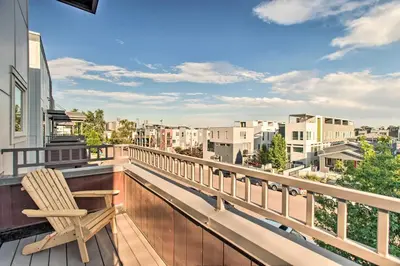 a chair on a balcony with a view of a city at Modern Denver Townhome with Rooftop Terrace! in Denver
