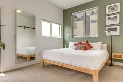 a bedroom with a large white bed and a mirror at Modern Denver Townhome with Rooftop Terrace! in Denver