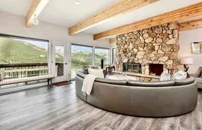 a living room with a large couch and a stone fireplace at Trails End Vacation Home at Windcliff home in Estes Park
