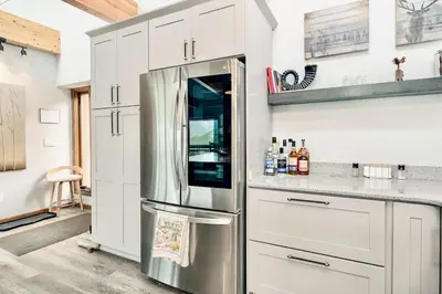 a kitchen with white cabinets and a stainless steel refrigerator at Trails End Vacation Home at Windcliff home in Estes Park