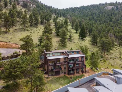 an aerial view of a house on a hill with trees at Trails End Vacation Home at Windcliff home in Estes Park