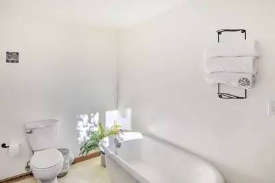 a white bathroom with a tub and a toilet and towels at Moose Park Lodge Charming Walden Retreat! in Walden